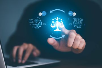 laptop with a glowing scale of justice icon surrounded by symbols