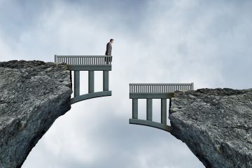Businessman stands on a broken bridge between two cliffs, facing a dangerous gap.