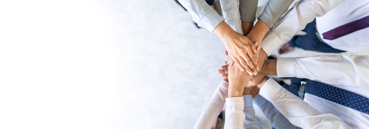 Group of diverse, business people with arms centred showing unity and teamwork.